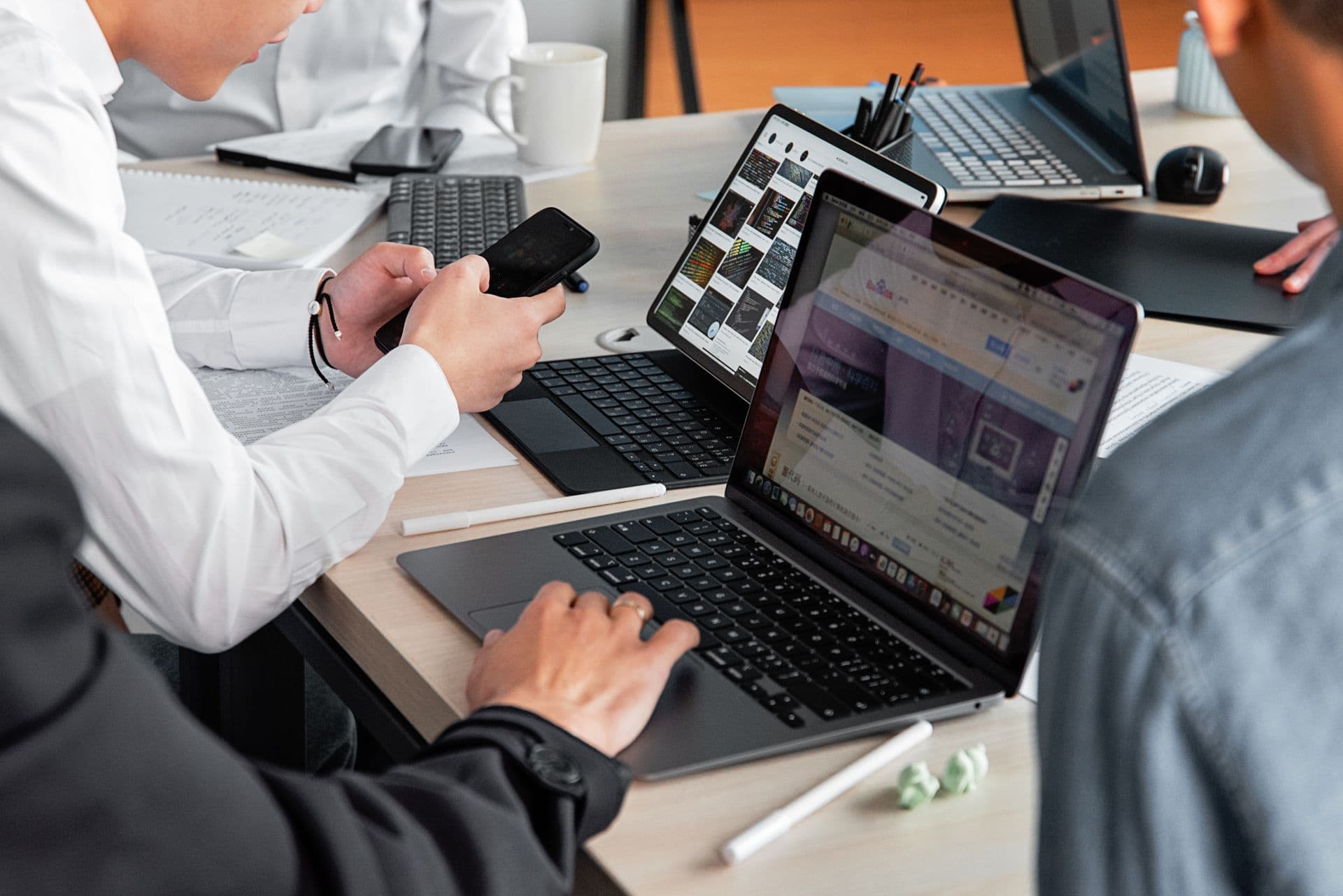 A product team at a shared desk, working on laptops and a phone